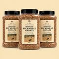 Three clear plastic jars of E&A Premium Foods Roasted Buckwheat Groats with black lids, arranged symmetrically on a light beige background.