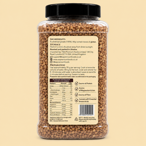 A clear plastic jar filled with brown textured grains or flakes, shown from the back with a black lid and a beige label containing text, nutrition facts, and a barcode on a pale beige background.